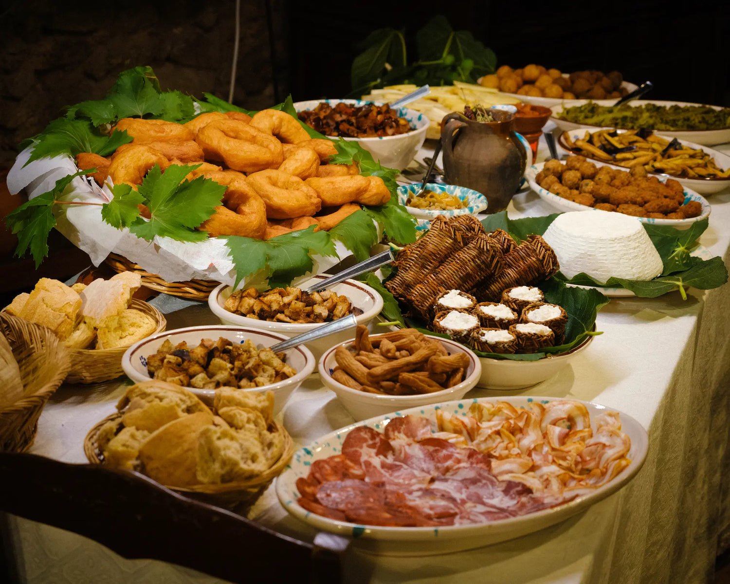 A table laden with many Calabrian foods, including curujicchi, ricotta, salame, and more!